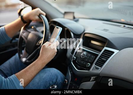 Hands of unrecognizable man driver using mobile phone while driving Stock Photo