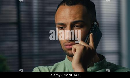 Serious worried excited latin american man talking mobile phone sad frustrated confused young businessman hear bad news feel stress experience have Stock Photo