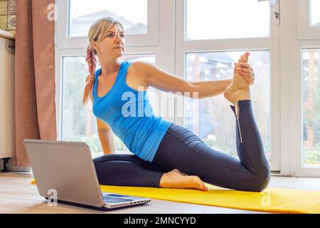 Beautiful woman in sportswear doing sport exercises on yoga mat at home Stock Photo