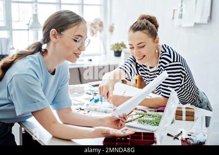 Successful Business Partners, small business partnership. Two Female jewelry artists designer, business owners making jewelry in their studio. Stock Photo