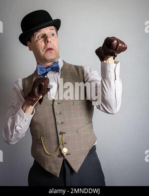 Man in Tweed Vest and Bowler Hat Punching Himself in the Stomach ...