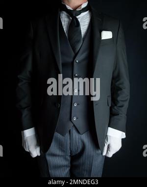 Portrait of Butler in Dark Suit and White Gloves Standing at Attention. Service Industry and Professional Hospitality. Stock Photo
