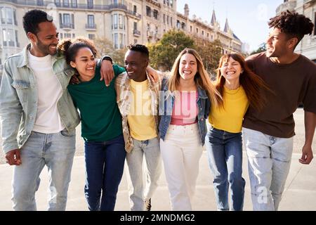 Happy international group of friends walking in the city street having fun together. Stock Photo