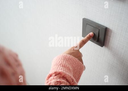 women finger turning on lighting switch . Stock Photo