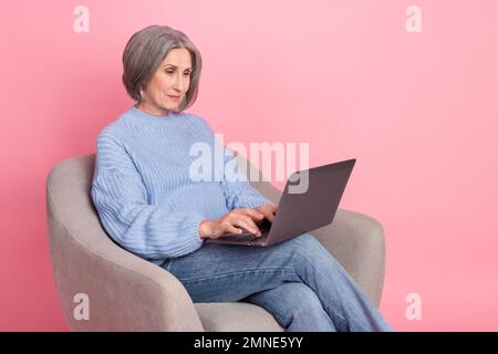 Photo of serious confident retired woman freelancer entrepreneur professional programmer typing new apple macbook isolated on pink color background Stock Photo