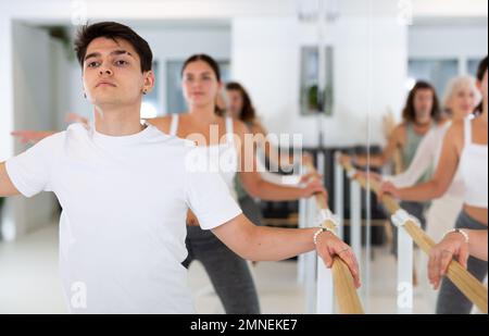 Diligent young man doing choreography at ballet barre Stock Photo