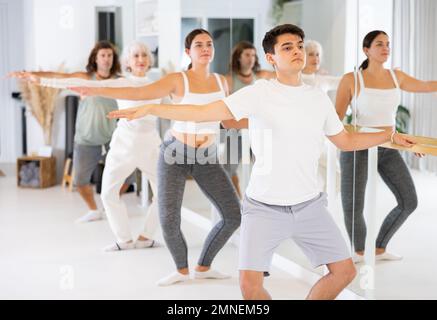 Diligent young man doing choreography at ballet barre Stock Photo