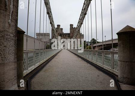 Thomas Telfords first suspension bridge 1826 over the River Conwy in N.Wales runs parallel to the rail and new road bridges with Conwy Castle beyond Stock Photo