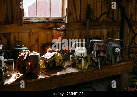 A row of vintage chainsaws on display in a row on a workbench in a barn at the Deerfield Fair, New Hampshire. Image was captured on analog color film. Stock Photo