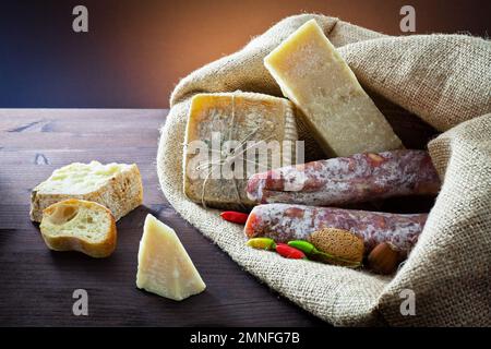 Typical Italian appetizer. Assortment of cheese, salami meats and hot pepper in jute bag. Snacks for wine. Stock Photo