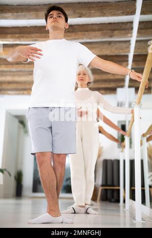 Concentrated women and men rehearsing ballet dance in dance studio Stock Photo