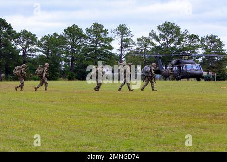 Soldiers of Squad 6, representing the U.S. Army National Guard, conduct hot load training with a UH-60 Black Hawk during the Army's first-ever Best Squad Competition held on Fort Bragg, North Carolina, Oct. 3, 2022. The Army Best Squad Competition tests Soldiers on their individual and collective ability to adapt to and overcome challenging scenarios and battle-readiness events, evaluating their physical endurance, technical skills, and tactical abilities under stress and extreme fatigue. Stock Photo