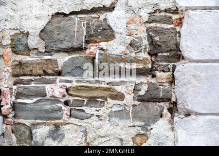 grey stucco wall with exposed stone, architectural textures Stock Photo