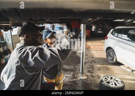 Mechanics wearing gloves replacing a car's tyres on a lift in an auto repair shop. High-quality photo Stock Photo