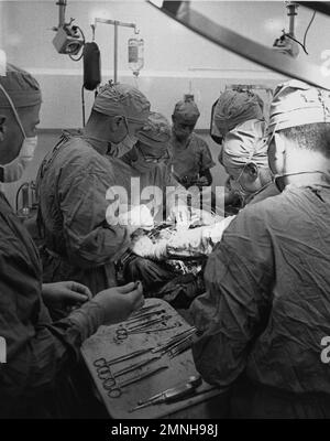 Scenes aboard the USS Repose (AH-16), a Haven-class hospital ship in operation during the Vietnam War. Here, doctors perform surgery on a wounded soldier ca. 1966 Stock Photo