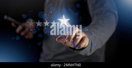 Satisfaction close up on customer man hand pressing on screen with five star rating feedback icon and press level excellent rank for giving best score Stock Photo