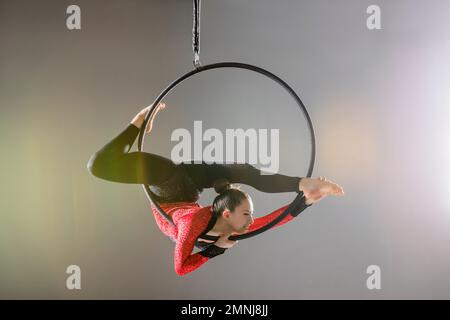 Young acrobat performing on aerial hoop Stock Photo