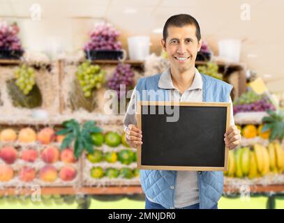 farmer holding an empty chalkboard at the fruits store Stock Photo