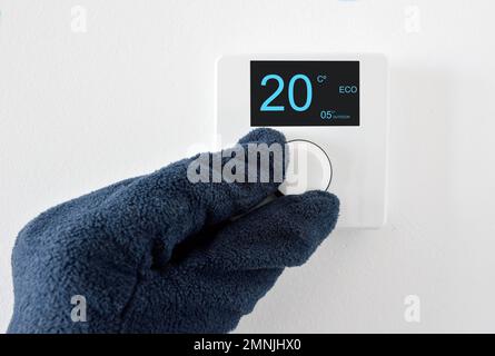 One hand with glove adjust thermostat digital in celsius at home Stock Photo