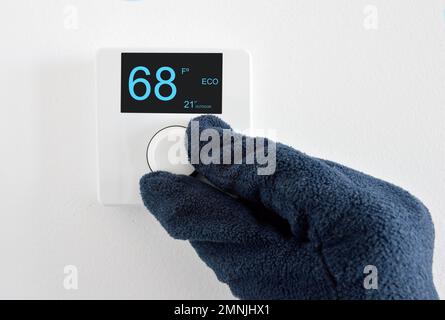One hand with glove adjust thermostat digital in fahrenheit at home Stock Photo