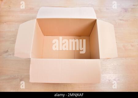 Flat lay of empty open cardboard box on wooden surface Stock Photo