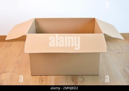 Flat lay of empty open cardboard box on wooden surface Stock Photo