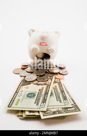 Piggy bank spewing out US coins and paper currency bank notes. Stock Photo