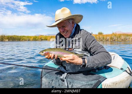 Senior fly fisherman holds rainbow trout before releasing back into spring creek Stock Photo