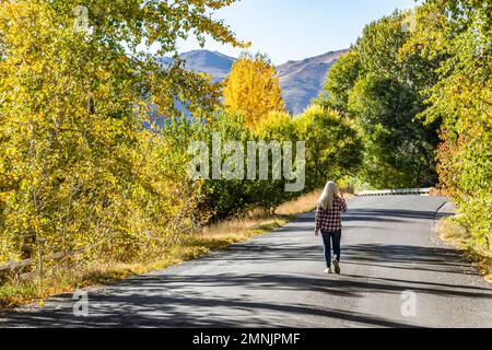 USA, Idaho, Bellevue, Senior woman walking on country road in fall Stock Photo