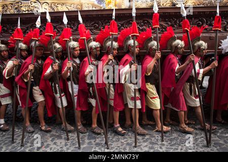 Men dressed as Roman soldiers carry a religious float with a statue of ...