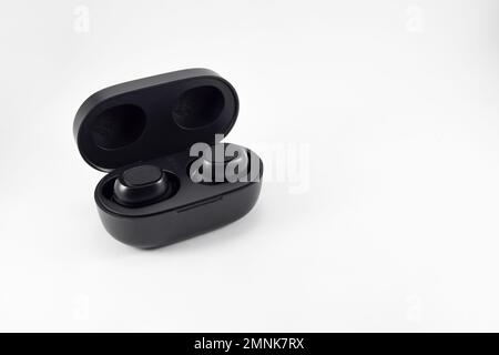 Wireless earphone bluetooth voice control with charger isolated on white background. Wireless earphones with its case opened. Stock Photo