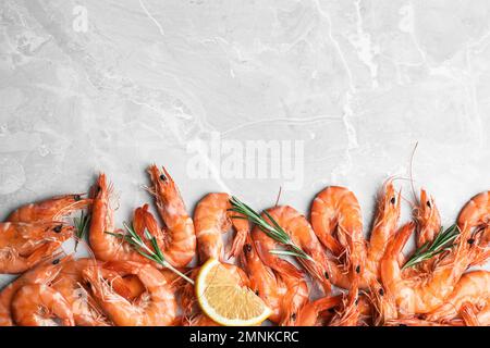 Delicious cooked shrimps with rosemary and lemon on grey marble table, flat lay. Space for text Stock Photo