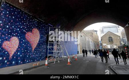 Australian street artist James Cochran also known as Jimmy C, works on his mural of eight hearts on a Network Rail wall at Borough Market in London, Sunday, March 25, 2018. (AP Photo/Kirsty Wigglesworth)