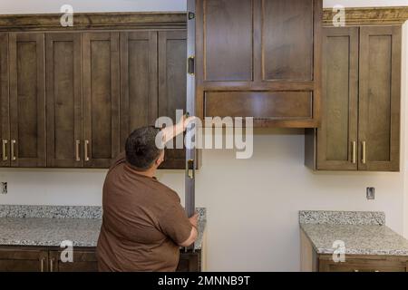 Worker hangs level at site for leveling of new kitchen cabinets furniture sets that are being installed Stock Photo