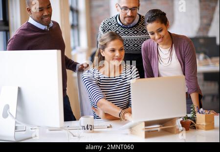 Producing impressive work as a team. a group of designers working together at a computer. Stock Photo