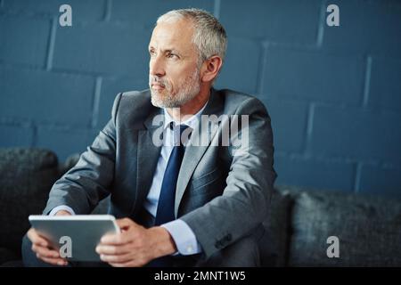 Thinking of the next big business venture. a thoughtful businessman using a digital tablet. Stock Photo