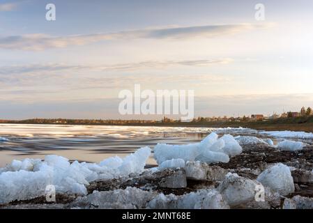 The remains of the last spring ice on the Vilyui River in Yakutia lie on the shore and float in the water against the backdrop of the forest during th Stock Photo