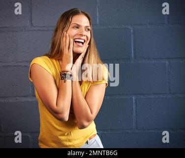 I did not see this coming. a young woman posing against a brick wall background. Stock Photo