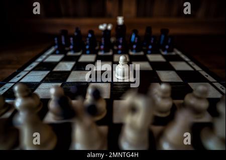 Blurred background with a low depth of focus. The set of wooden chess pieces elements standing on chess board on dark background. Leadership, teamwork Stock Photo