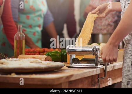 Fresh pasta is the best pasta. a woman making fresh pasta with people standing in the background. Stock Photo