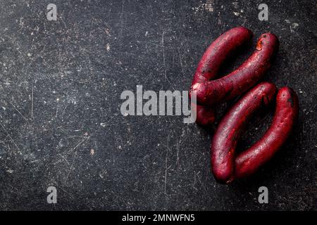 Smoked pork sausage on the black table. Top view. Stock Photo
