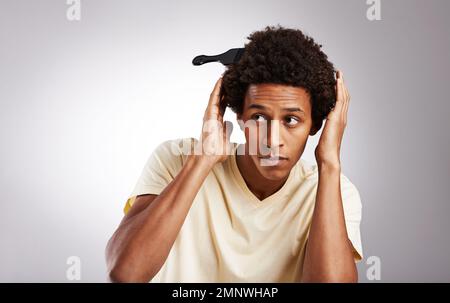 Keep calm and flaunt your afro. Studio shot of a young man posing with his afro comb in his hair. Stock Photo
