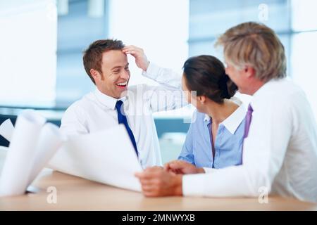 Happily working team. Smiling executives sitting at table and discussing a project. Stock Photo