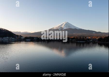 Mount Fuji on a bright winter morning, as seen from across lake Kawaguchi, and the nearby town of Kawaguchiko. Stock Photo