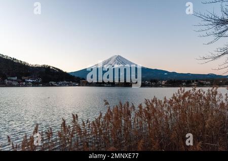 Mount Fuji on a bright winter morning, as seen from across lake Kawaguchi, and the nearby town of Kawaguchiko. Stock Photo
