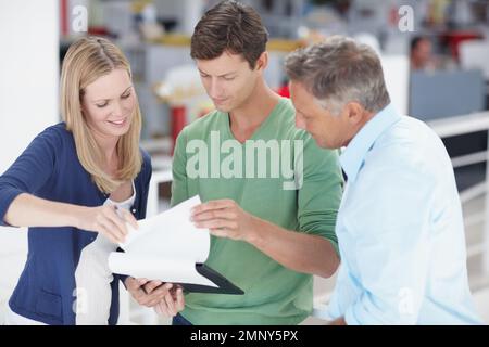 Making some last minute adjustments. Three work colleagues discussing something work related. Stock Photo