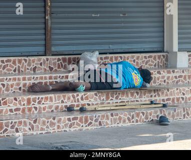 Handicapped man - invalid, lying on the stairs in front of the closed metal gate, Thailand 2023. Stock Photo