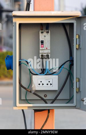 An open metal box with no-fuse breaker and socket instal on a mast on street Stock Photo