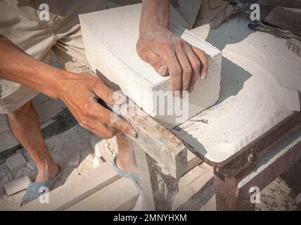 The sculptor's hands, which process a block of white stone on the desktop with tools. Hand Detail Stock Photo