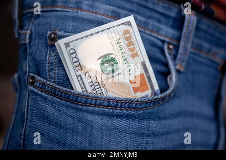 Many dollar 100 banknotes in a jeans pocket. One hundred dollar bills in a pocket of favorite trousers. Stock Photo